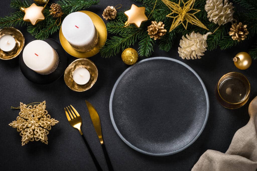 christmas table setting with holiday decorations at black background.