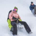 crazy happy friends having fun with sledding on snow high mountains focus on right girl